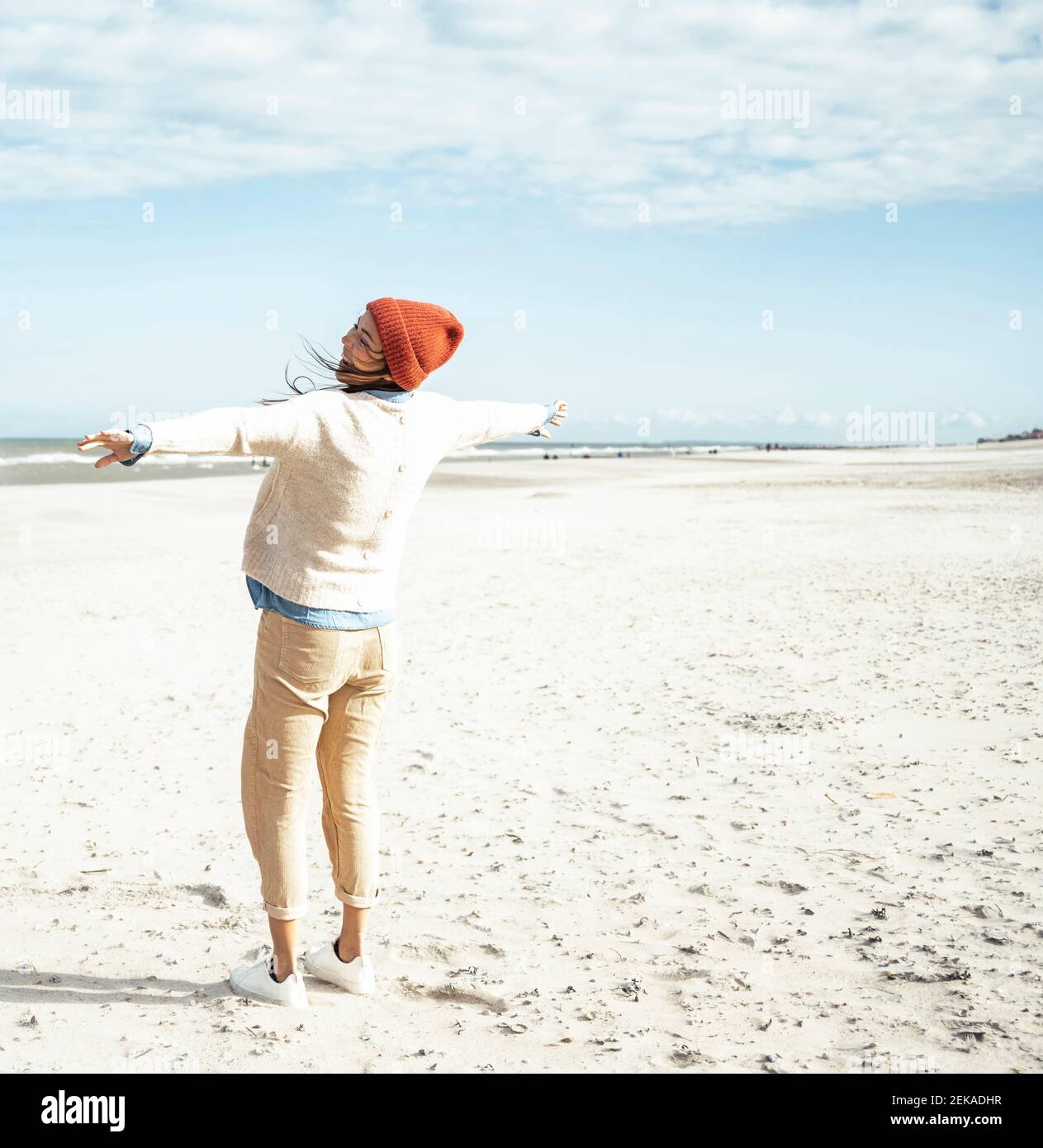 Giovane donna in piedi sulla spiaggia di sabbia con braccia sollevate Foto Stock