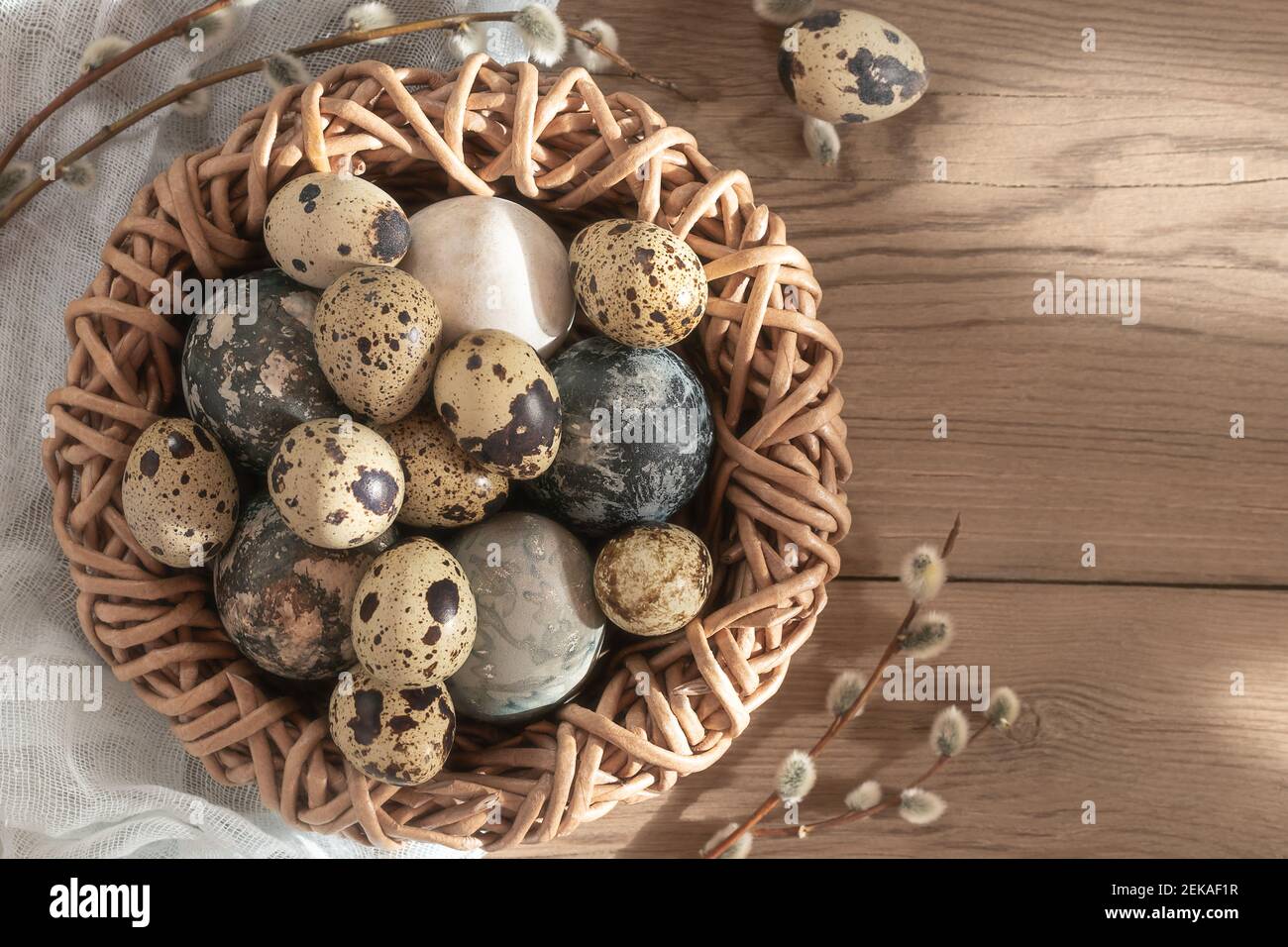 Composizione di Pasqua - uova di Pasqua dipinte con coloranti naturali in un nido di vimini su un tavolo di legno, copyspace. Foto Stock