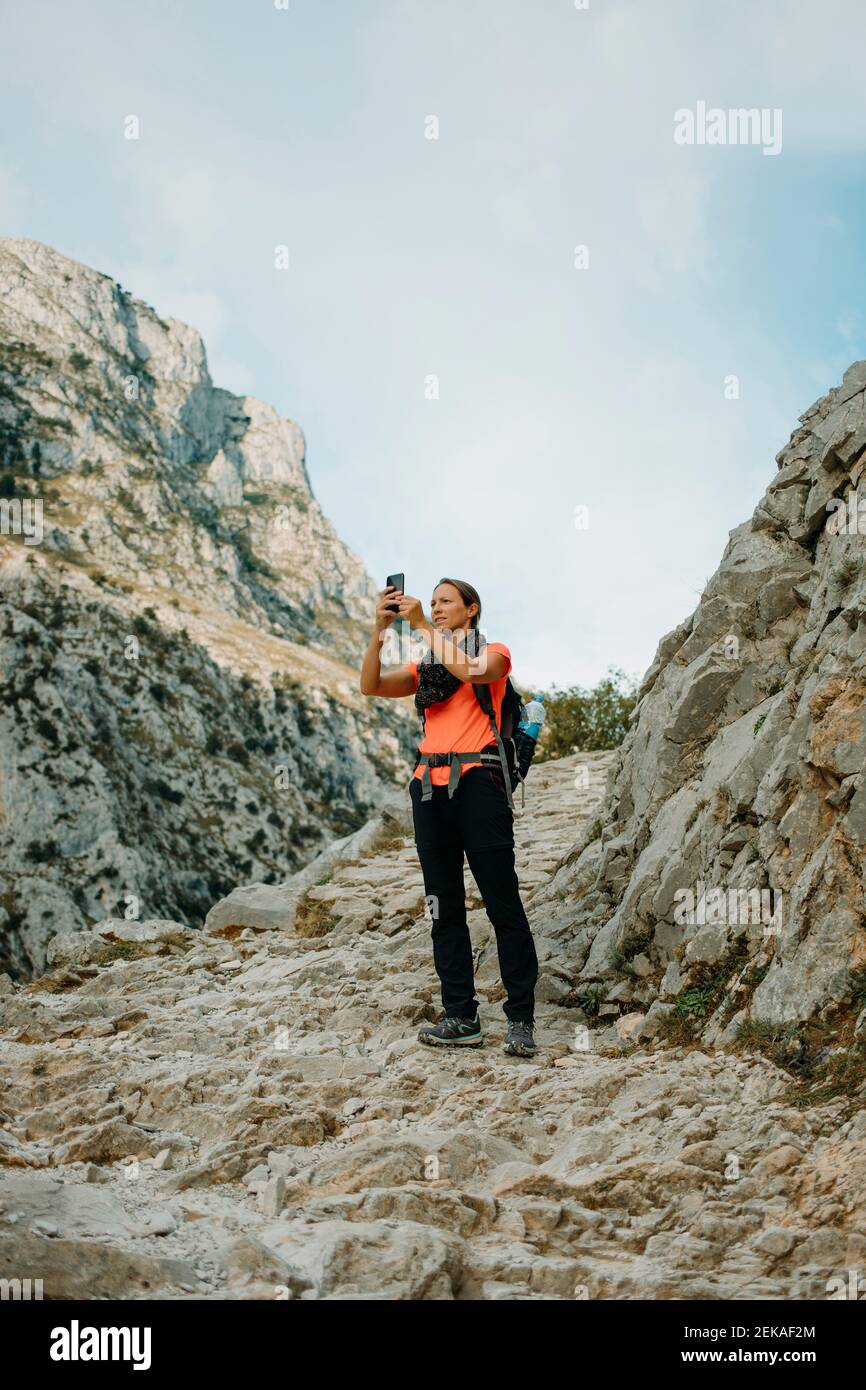 Donna esploratore con il telefono cellulare mentre si è in piedi a Cares Trail nel Parco Nazionale Picos De Europe, Asturias, Spagna Foto Stock