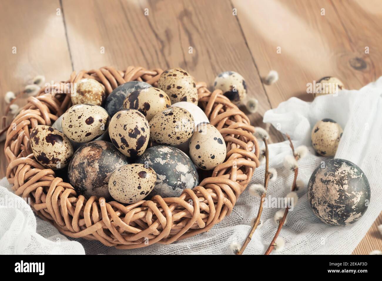 Composizione di Pasqua - uova di Pasqua dipinte con coloranti naturali in un nido di vimini su un tavolo di legno, copyspace. Foto Stock