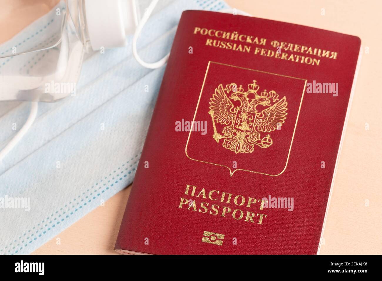 Viaggio sicuro durante il concetto di pandemia di coronavirus. Maschera medica protettiva, occhiali da sole, disinfettante e passaporto russo sul tavolo. Foto Stock