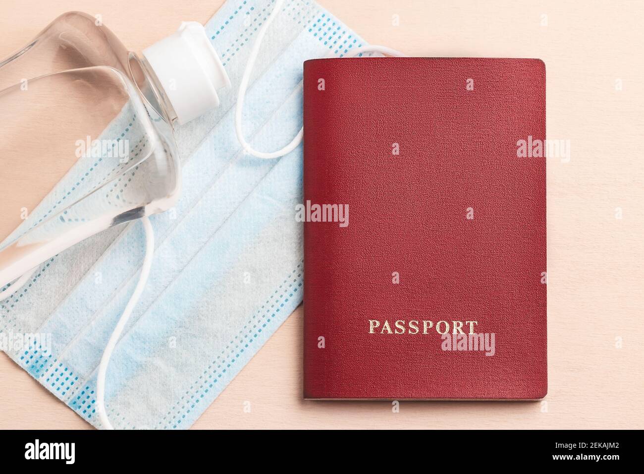 Viaggio sicuro durante il concetto di pandemia di coronavirus. Maschera medica protettiva disinfettante e passaporto sul tavolo, flatlay. Foto Stock