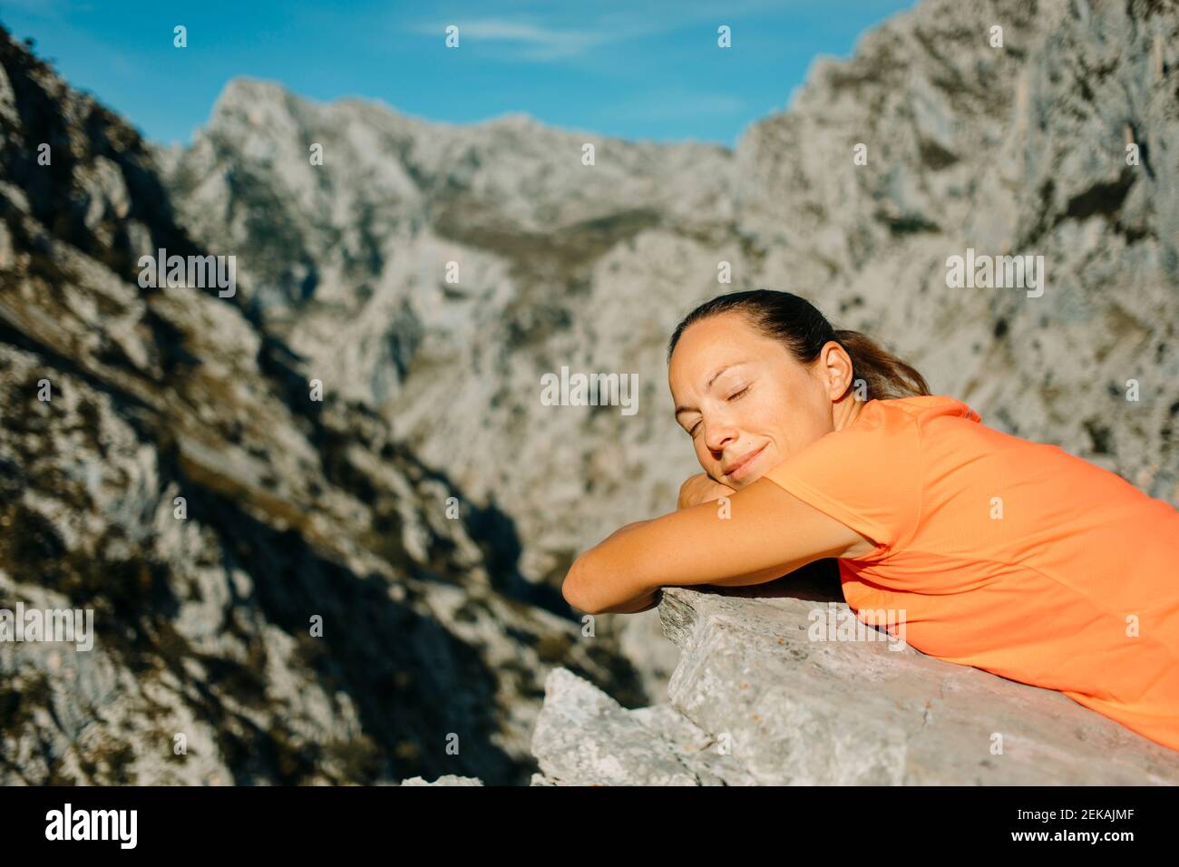 Donna con gli occhi chiuso rilassandosi sulla roccia al Cares Trail nel Parco Nazionale Picos De Europe, Asturie, Spagna Foto Stock