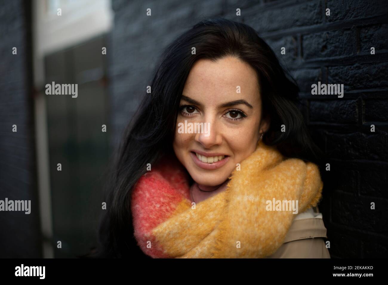 Sorridente bella donna contro muro nero Foto Stock
