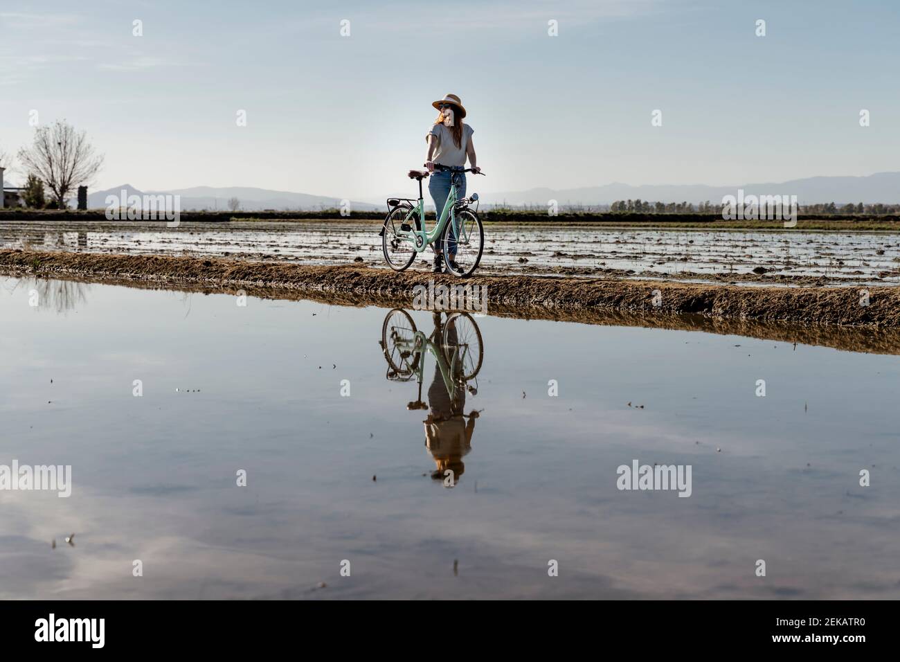 Giovane donna in piedi con la bicicletta contro il cielo al Delta di Ebro durante le vacanze, Spagna Foto Stock