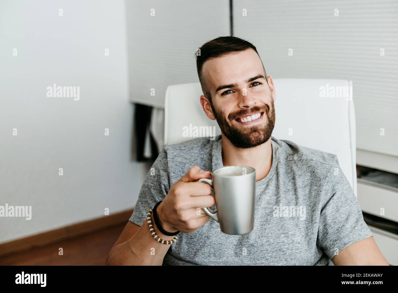 Uomo sorridente che prende una pausa dal lavoro a casa Foto Stock