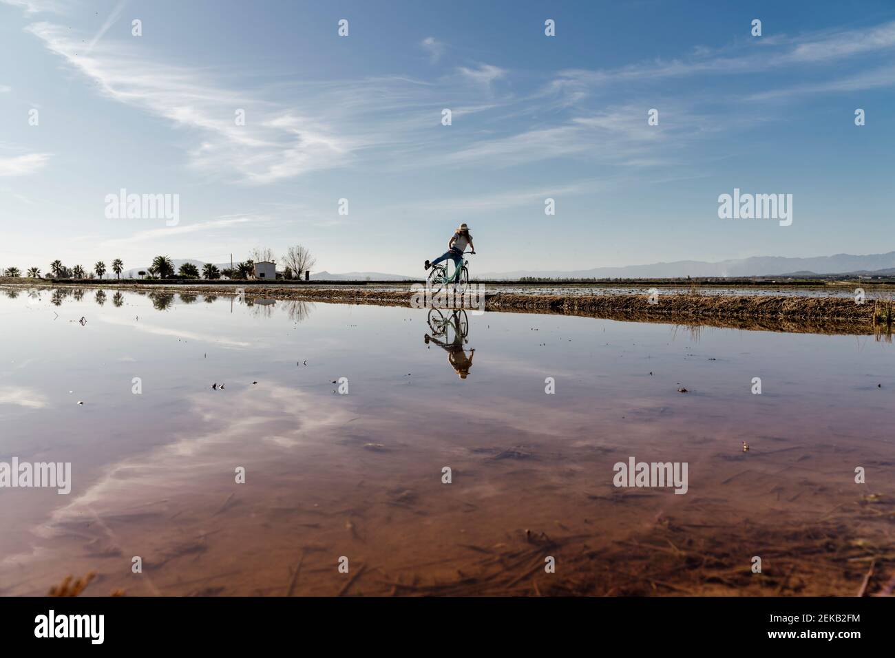 Giovane donna allegra che cavalca il cielo in bicicletta nella giornata di sole al Delta di Ebro, in Spagna Foto Stock