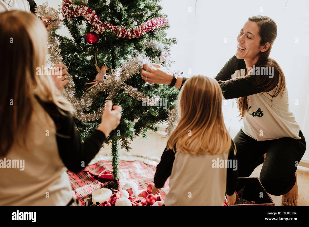 Fratello e sorelle che decorano l'albero di Natale a casa Foto Stock