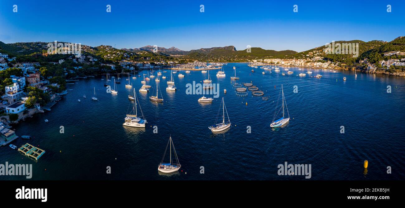 Spagna, Maiorca, Andratx, elicottero vista delle barche che navigano vicino alla riva della città costiera al tramonto d'estate Foto Stock