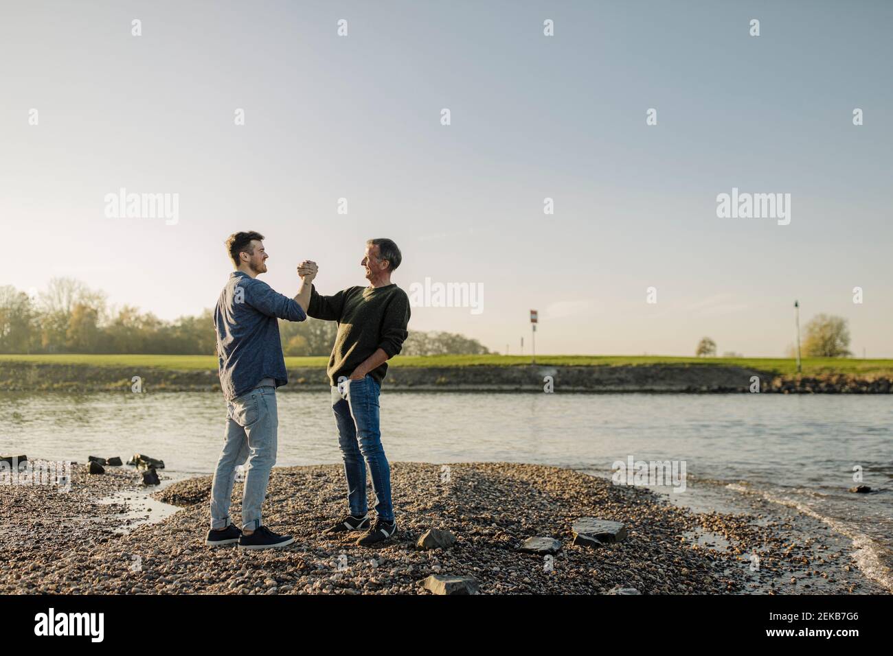 Padre e figlio contro il cielo limpido sulla riva del fiume Foto Stock