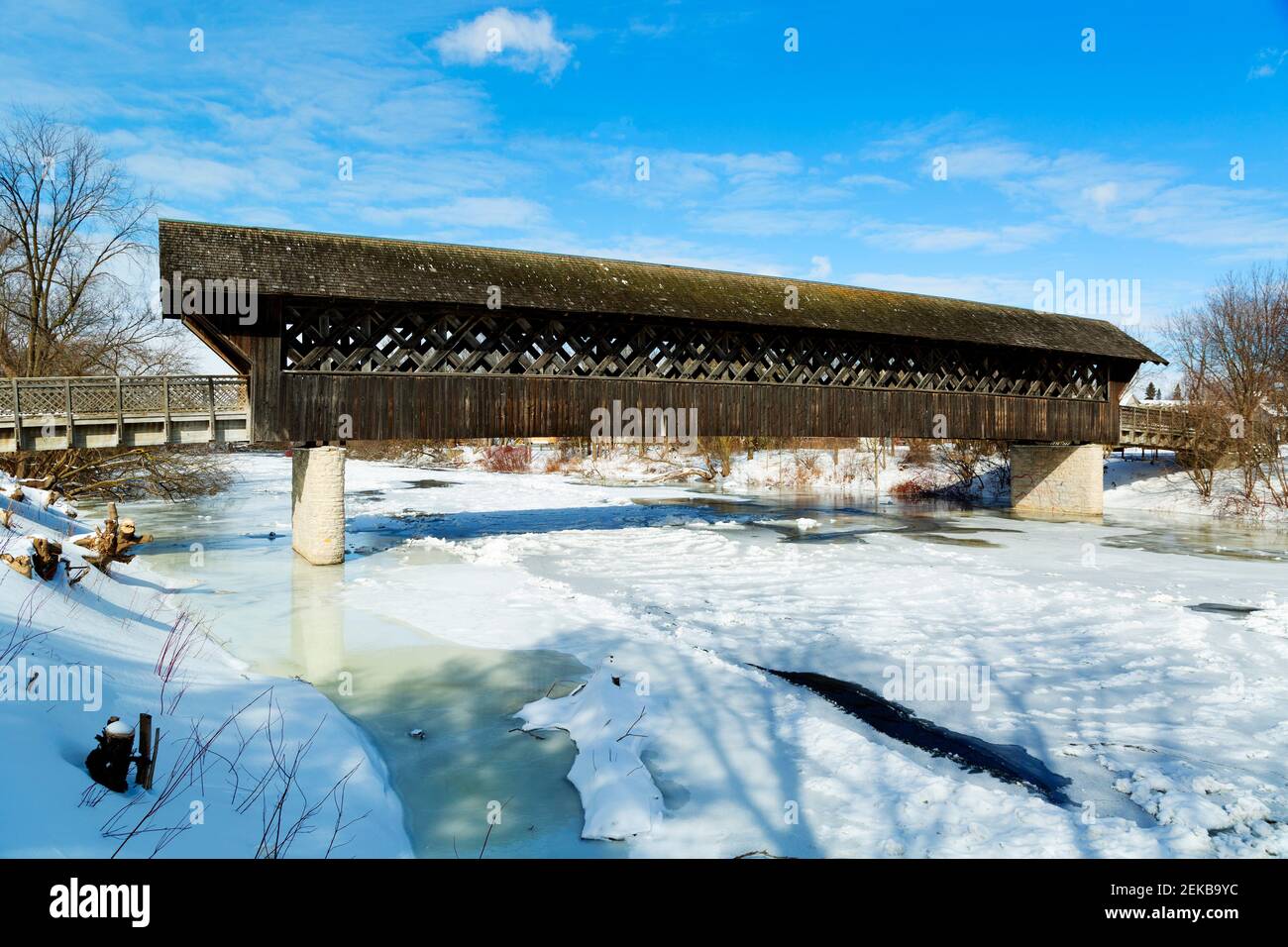 Il ponte pedonale coperto interamente in legno e ciclista sul fiume Eramosa in inverno, costruito nel 1992. Guelph, Ontario, Canada Foto Stock