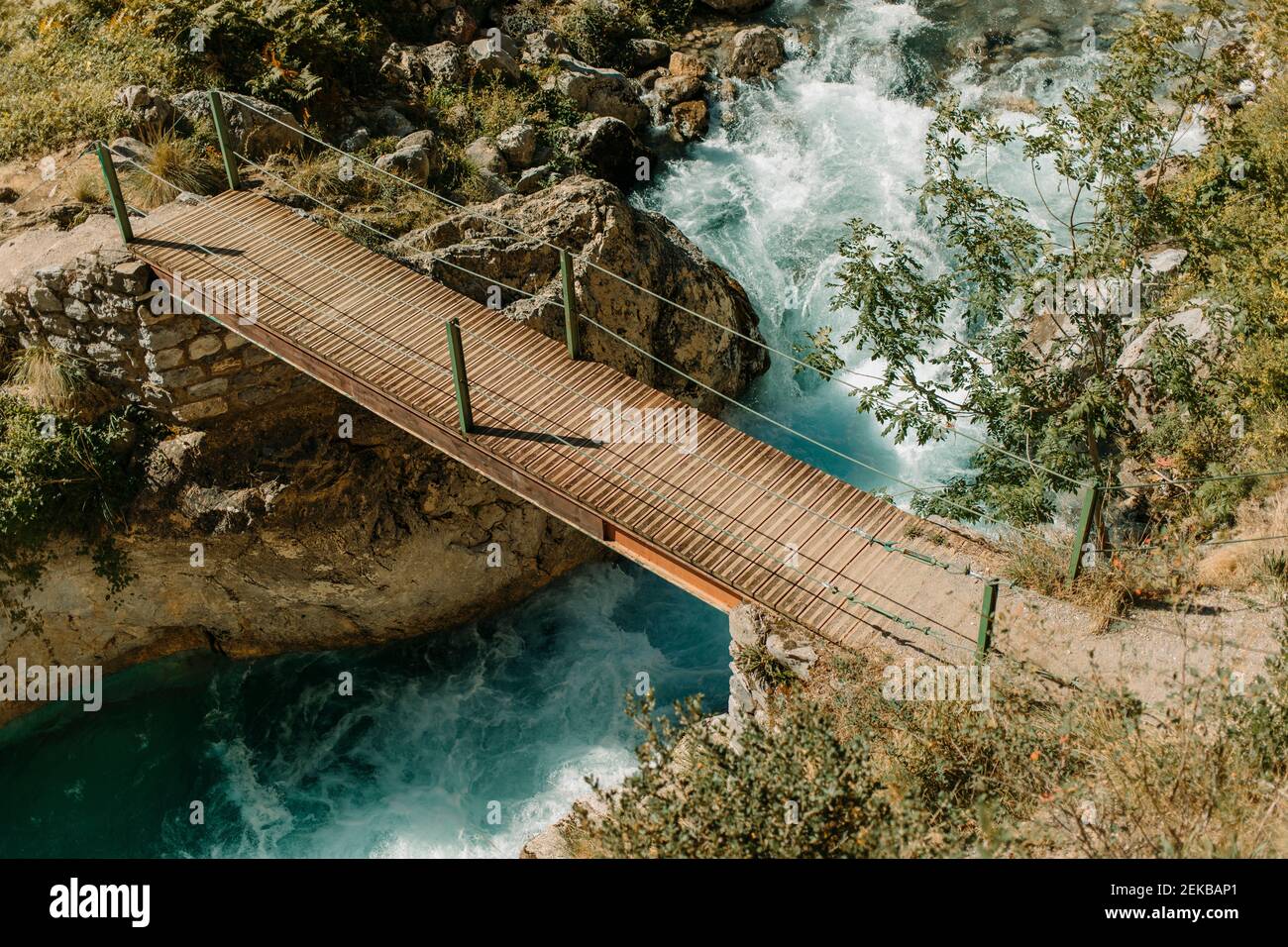 Ponte di legno sul fiume che scorre a Cares Trail nel Parco Nazionale Picos De Europe, Asturias, Spagna Foto Stock