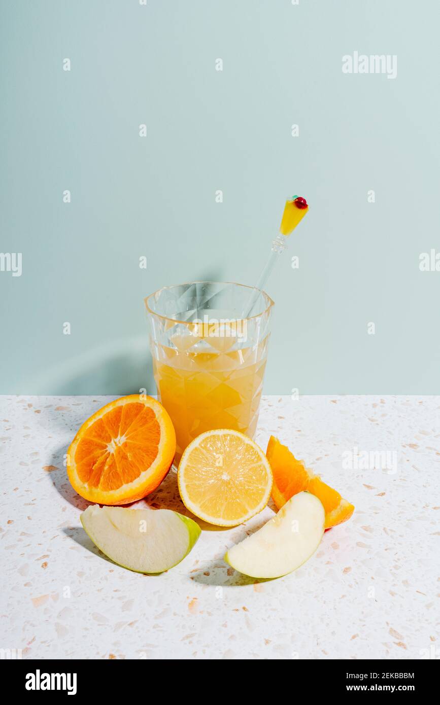 Succo estivo di frutta con arancia, limone e mela su marmo di terrazzo contro il muro Foto Stock