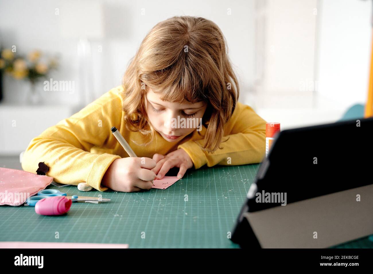 Cute ragazza disegno su carta con tablet digitale sulla scrivania a casa Foto Stock