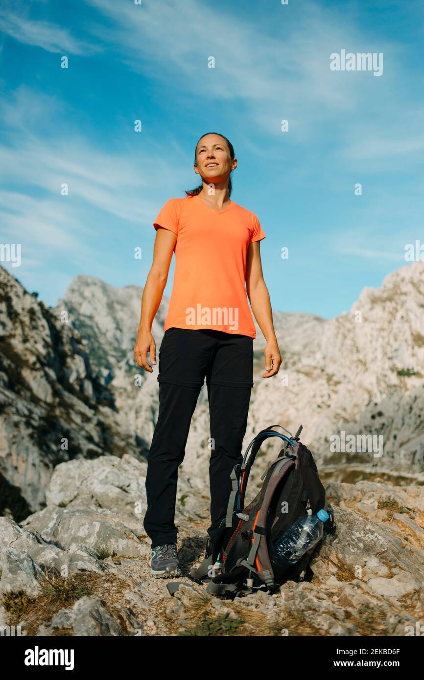 Donna escursionista con zaino che guarda la vista mentre si trova a Cares Trail nel Parco Nazionale Picos De Europe, Asturias, Spagna Foto Stock