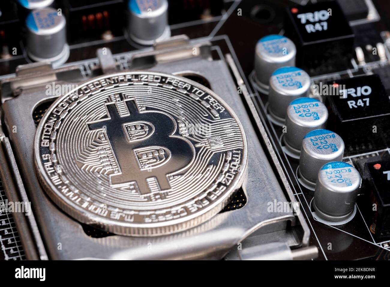 Crypto Currency su mercati azionari globali e concetto finanziario: Ripresa macro di una moneta bitcoin argento in una scheda principale di circuito di computer. Elemento economico Foto Stock