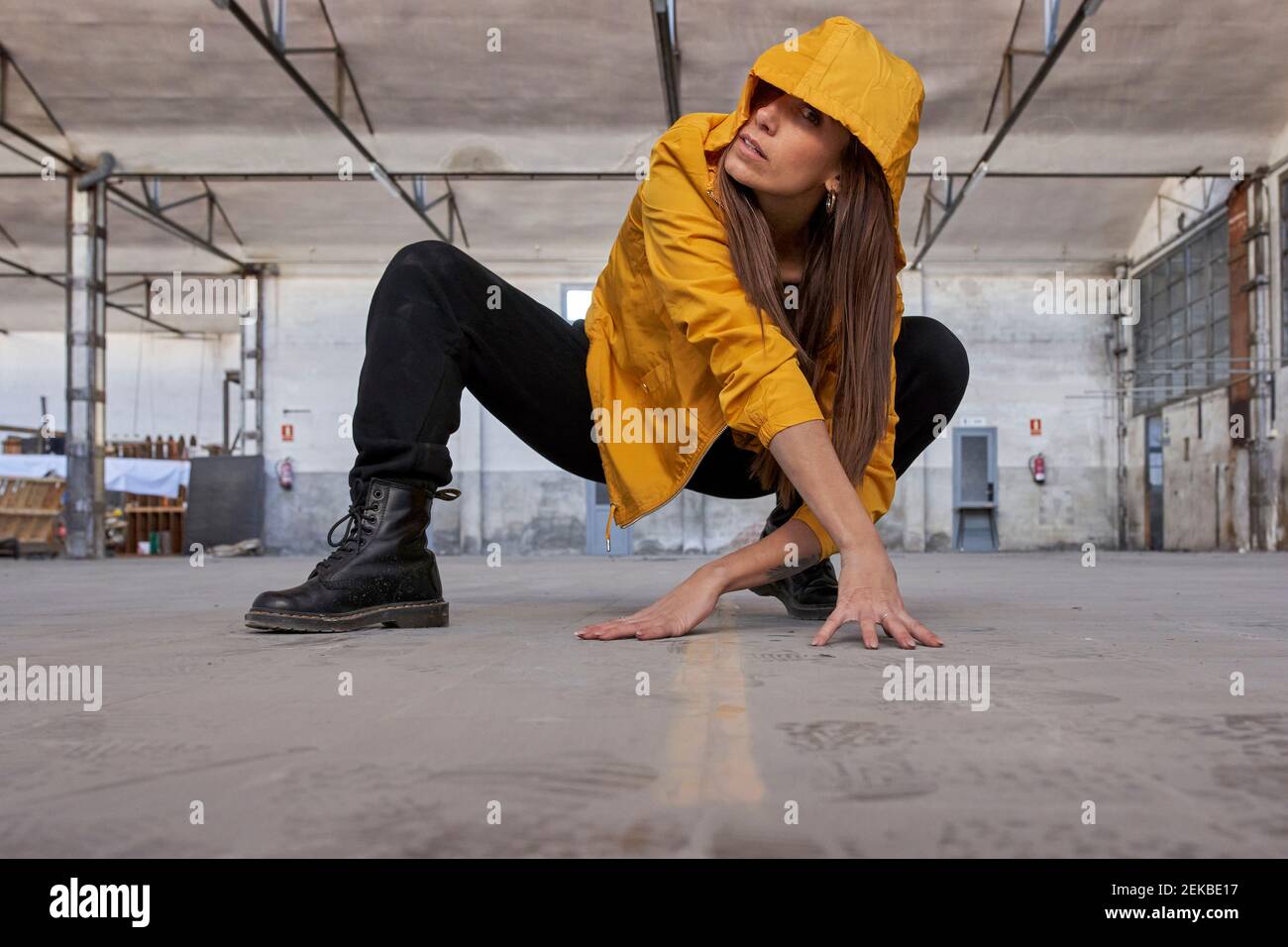 Danzatrice moderna in giacca gialla che pratica la danza in fabbrica abbandonata Foto Stock