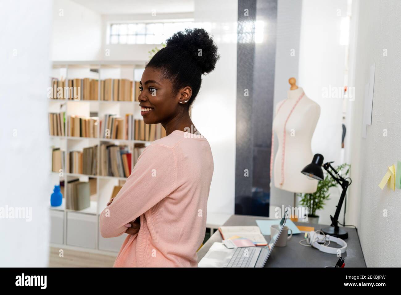 Un designer di moda sorridente mentre si trova in ufficio a casa Foto Stock