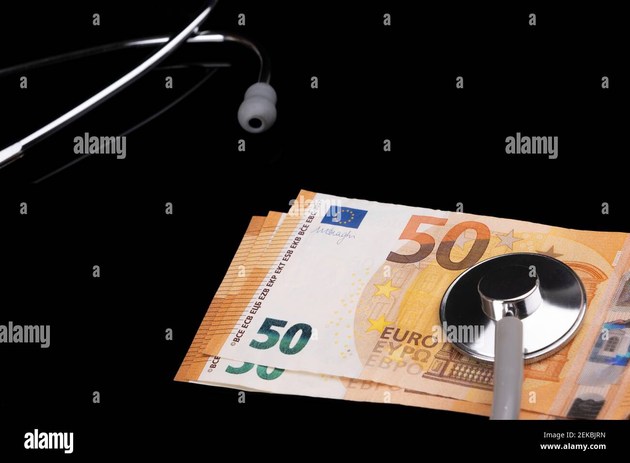 Concetto sanitario, assicurativo ed economico: Cinquanta banconote europee CON stetoscopio giacciono su sfondo nero. Sicurezza sociale Foto Stock