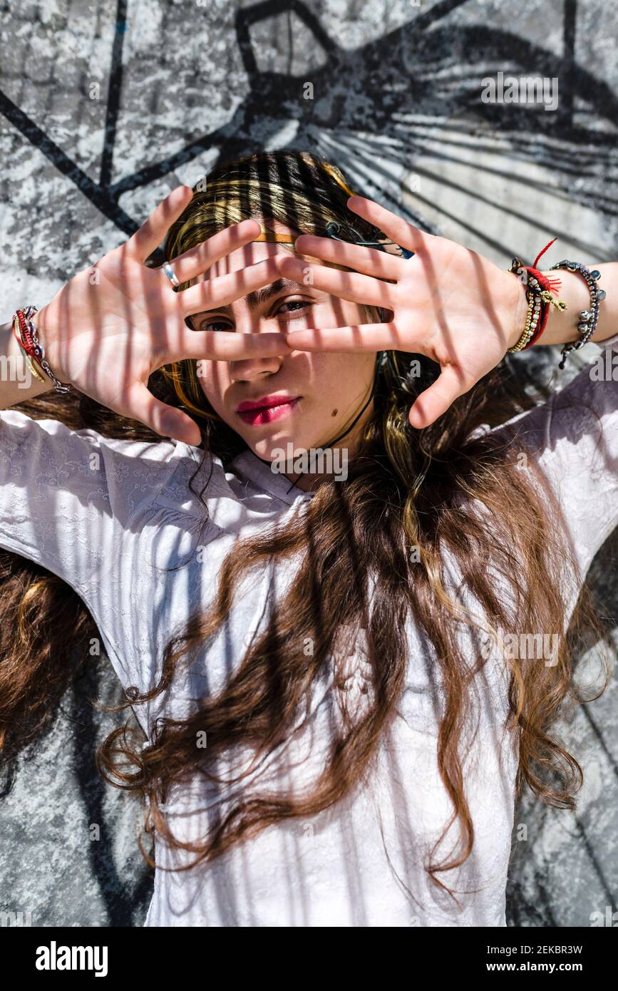 Giovane donna che nasconde il viso con le mani mentre si trova su pavimento in cemento Foto Stock