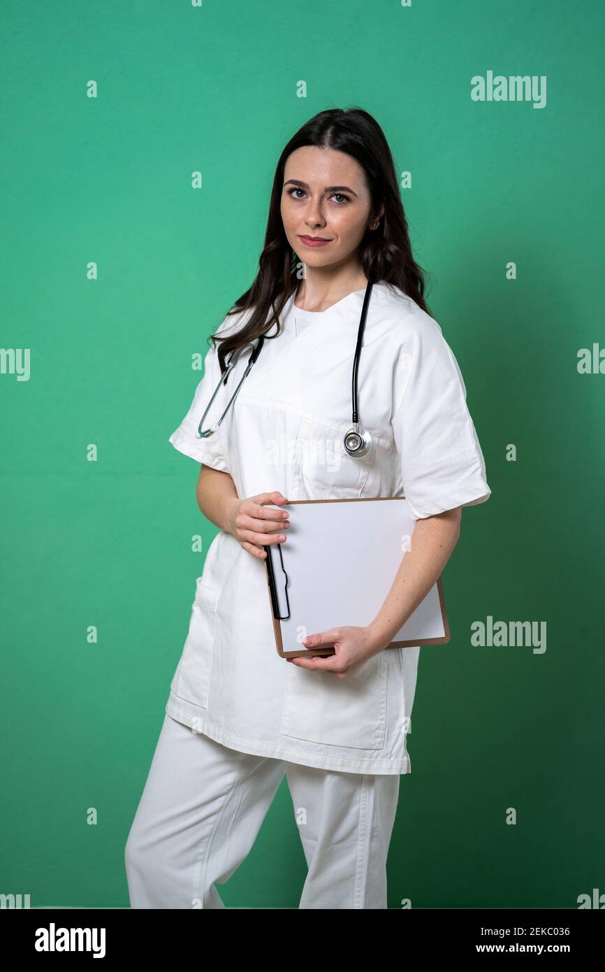 Giovane dottore femminile con appunti e stetoscopio su sfondo verde Foto Stock