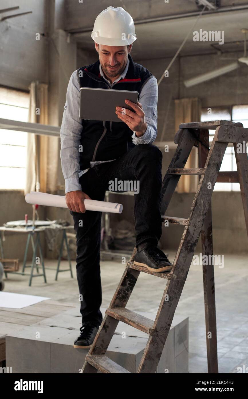 Ingegnere maschile che utilizza un tablet digitale mentre si sta in piedi nella costruzione a. sito Foto Stock