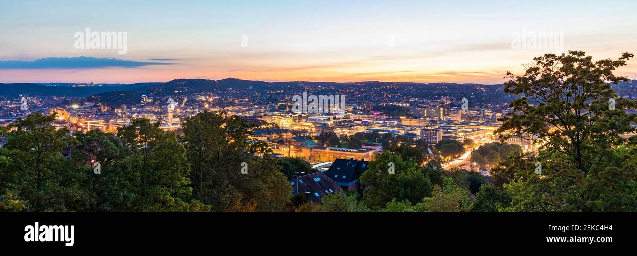 Germania, Baden-Wurttemberg, Stoccarda, panorama del centro città illuminato visto dalla cima della collina di Uhlandshohe al crepuscolo Foto Stock