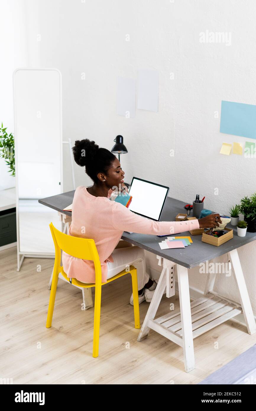 Stilista di moda che lavora mentre si siede in ufficio domestico Foto Stock