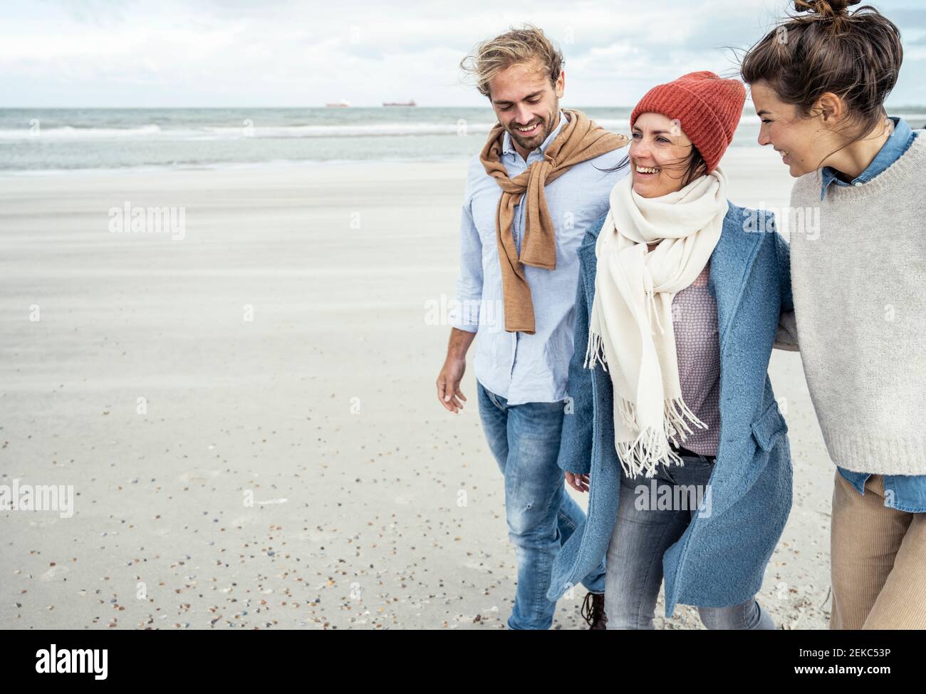 Gruppo di amici che camminano insieme lungo la spiaggia costiera sabbiosa Foto Stock