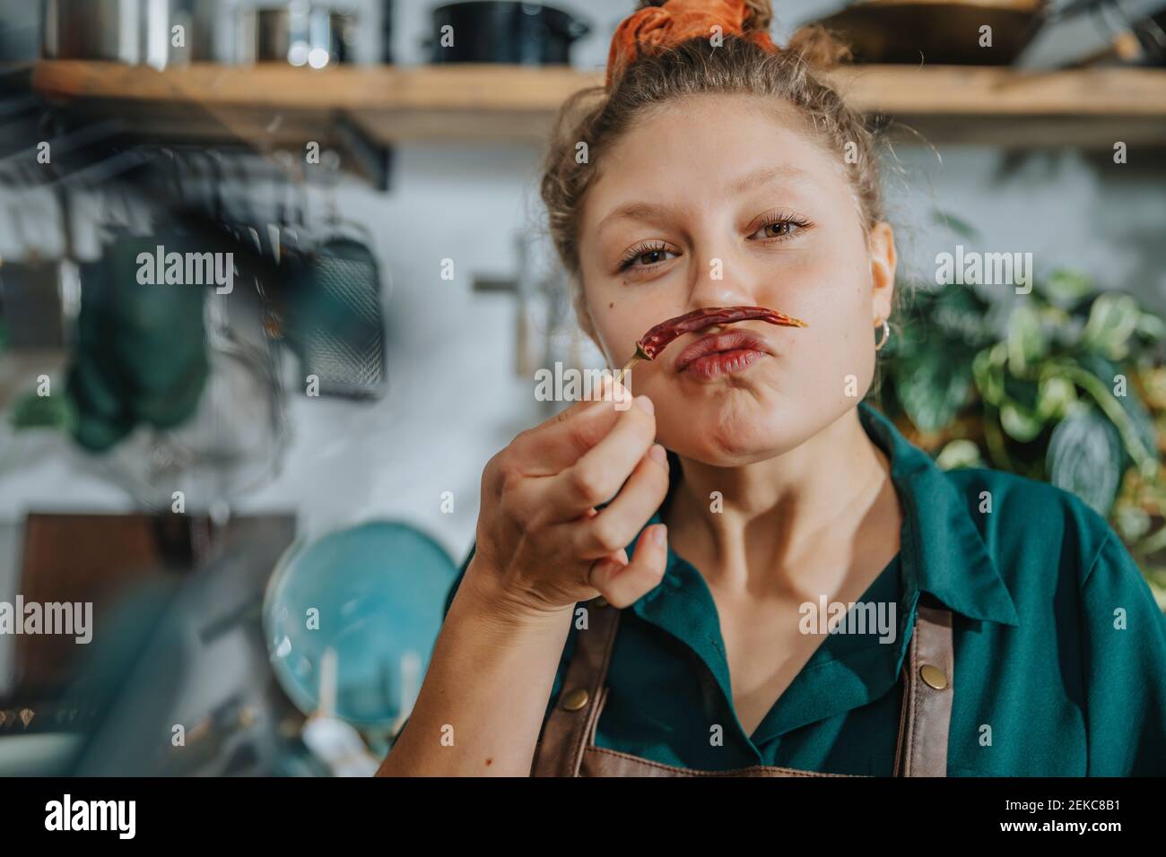 Cuoco giocoso che prepara baffi con peperoncino secco mentre si è in piedi in cucina Foto Stock