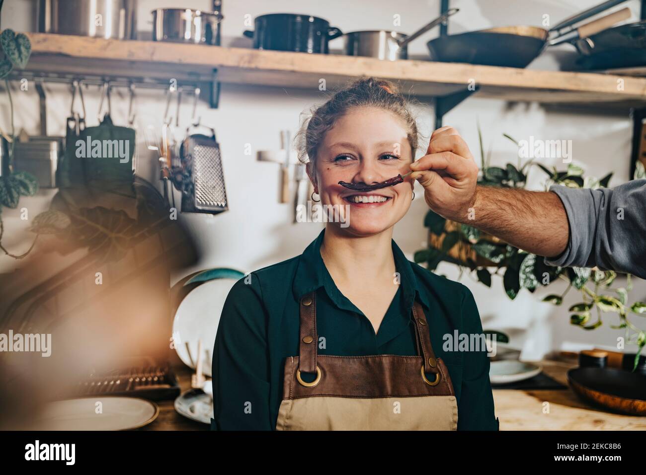 Chef che prepara baffi di peperoncino secco al collega mentre si è in piedi in cucina Foto Stock