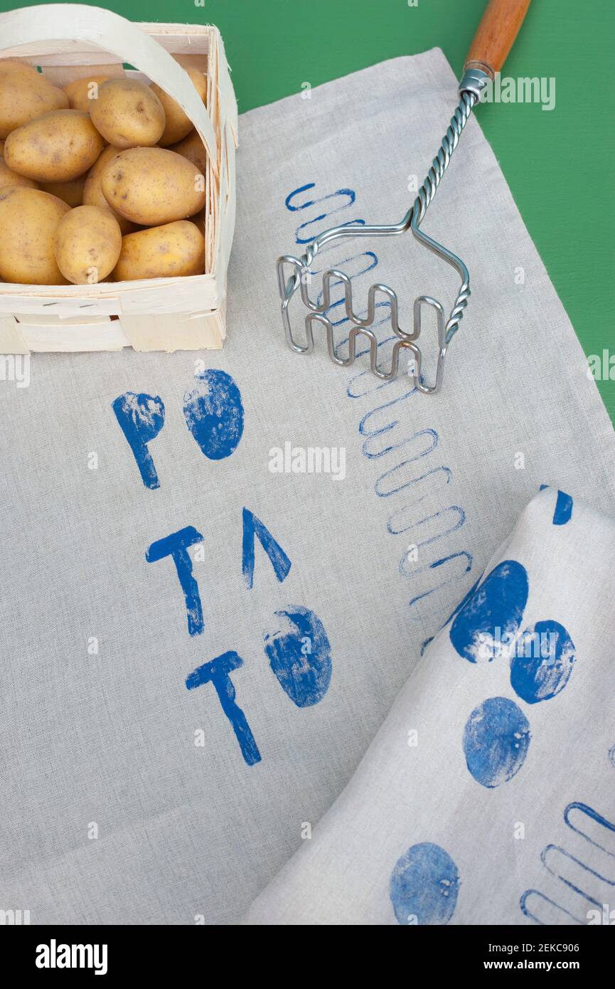 Cesto di patate crude, rasher di patate e tessuto ricoperto di stampe blu Foto Stock