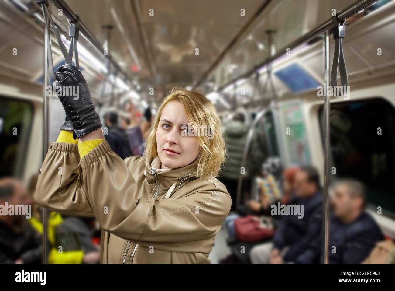 La giovane donna europea corre in piedi nell'abitacolo della carrozza della metropolitana. Foto Stock