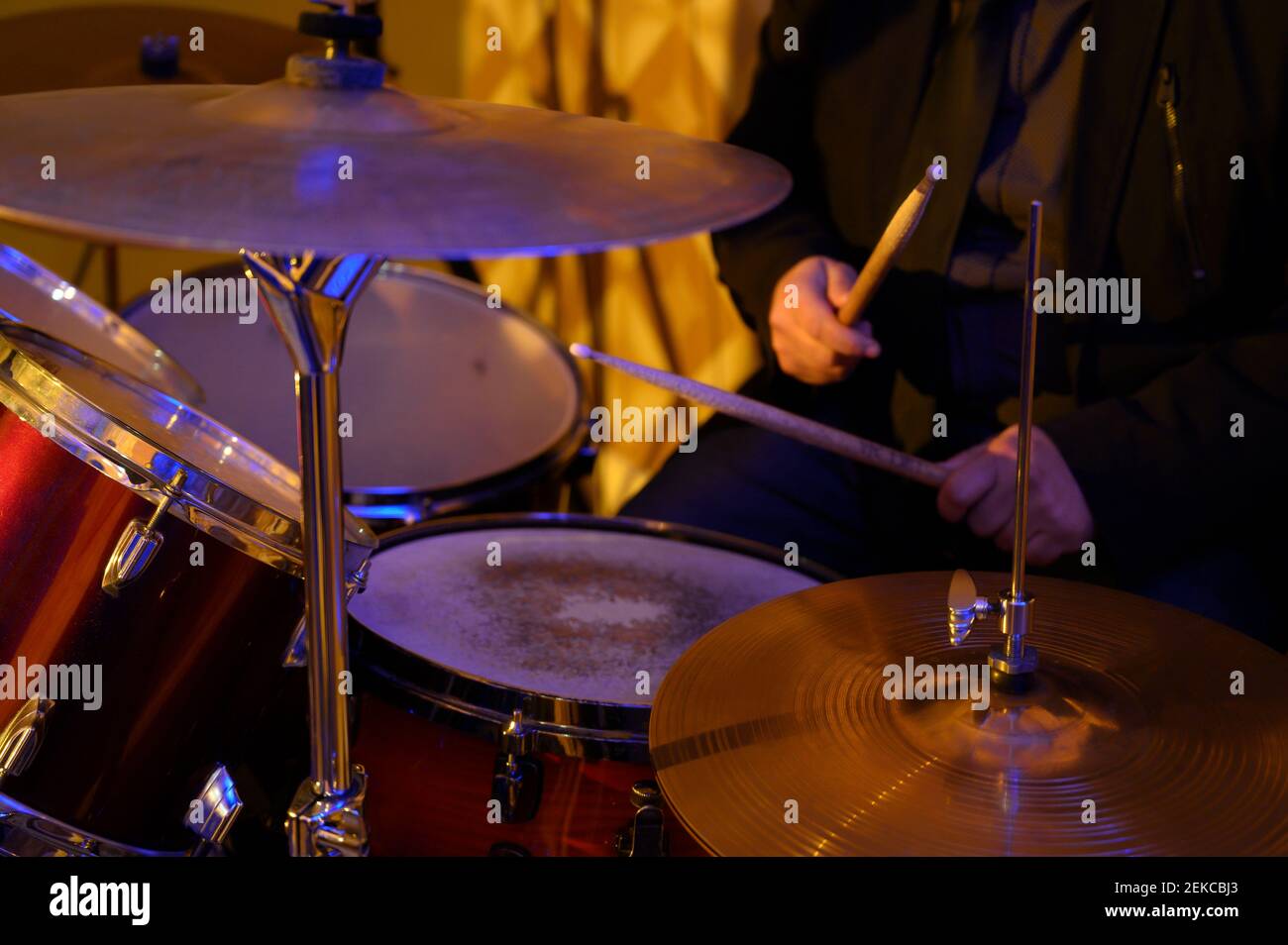 Musicista rock maschile che pratica con la batteria in studio Foto Stock