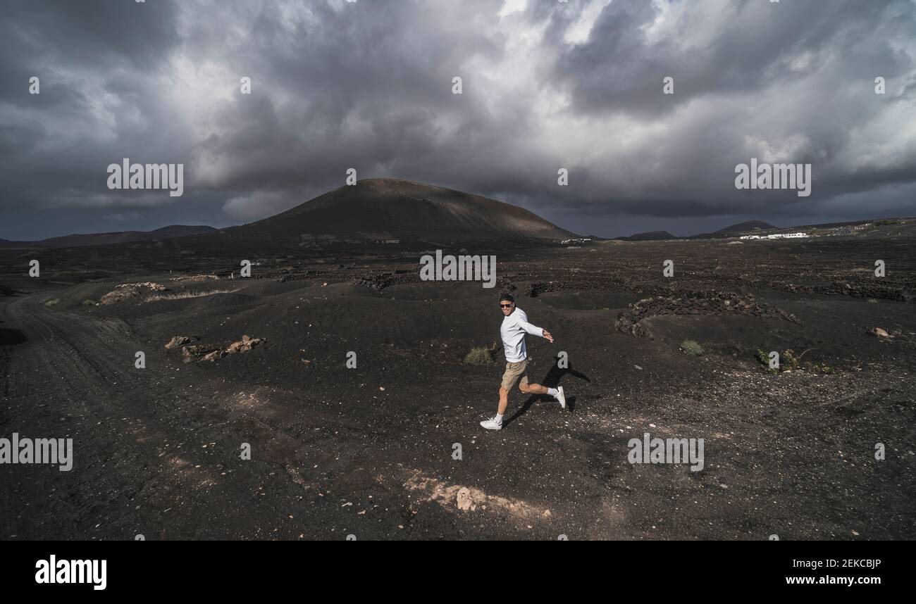 Buon turista maschio ballare sulla cenere del vulcano El Cuervo, Lanzarote, Spagna Foto Stock