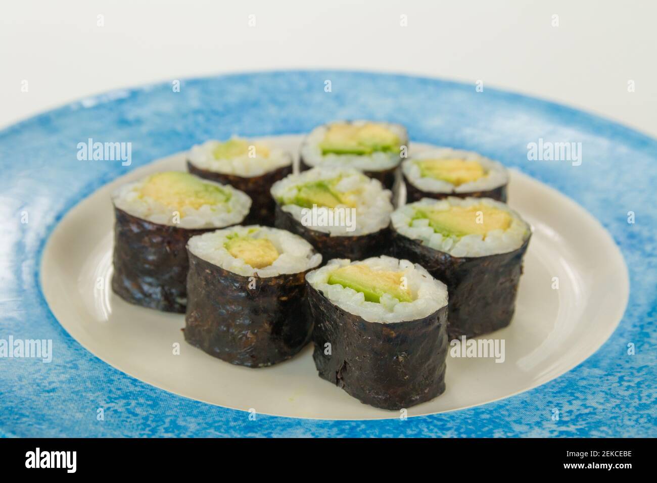 Sushi vegetariano con avocado su piatto bianco e blu isolato su sfondo bianco Foto Stock
