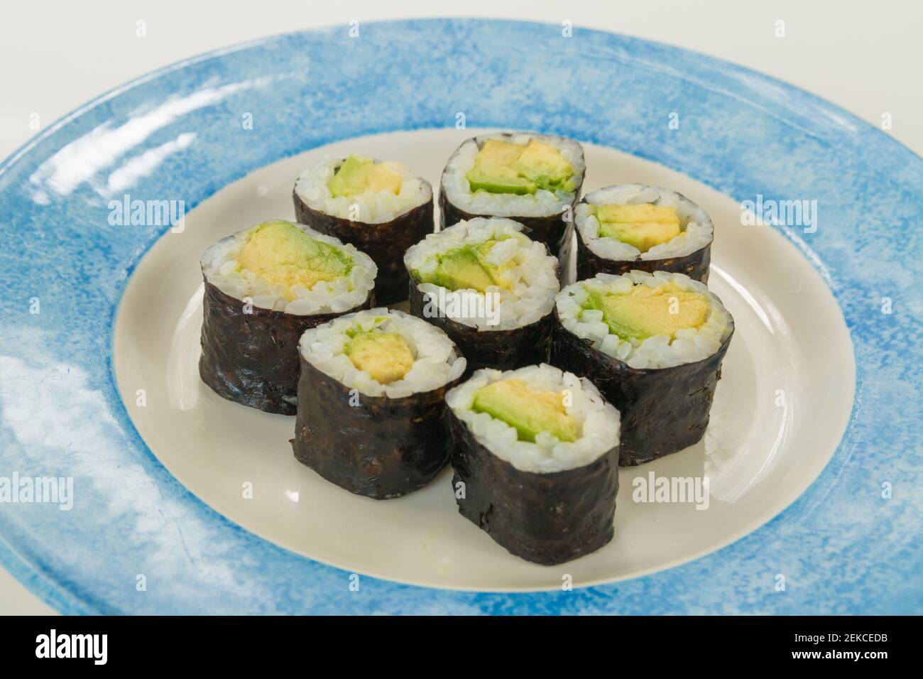 Sushi vegetariano con avocado su piatto bianco e blu isolato su sfondo bianco Foto Stock