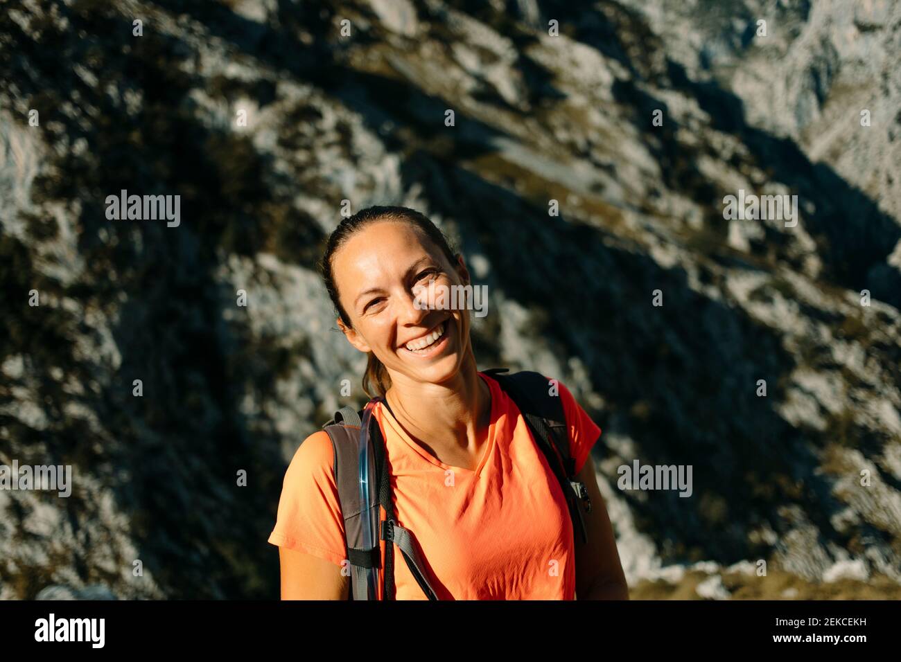 Donna felice con zaino in piedi contro la montagna a Cares Trail nel Parco Nazionale Picos De Europe, Asturias, Spagna Foto Stock