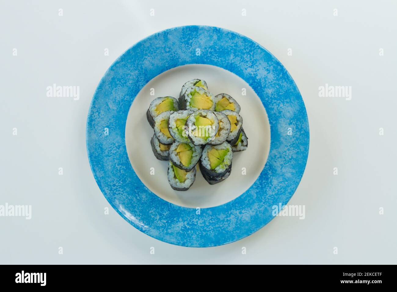 Involtini vegetariani di sushi con avocado su piatto bianco e blu isolato su sfondo bianco Foto Stock