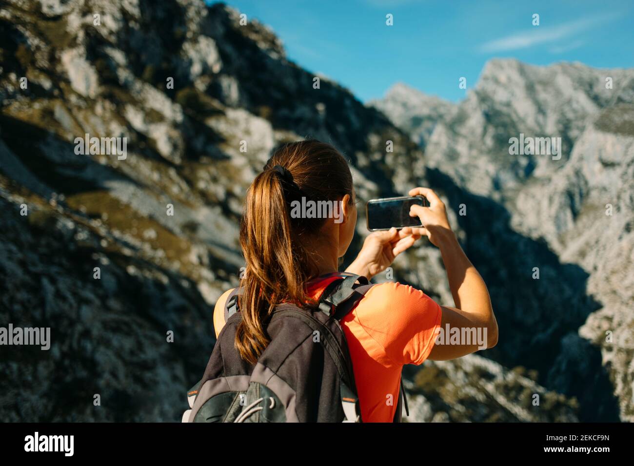Escursionista scattare foto tramite telefono cellulare mentre si è in piedi al Cares Trail nel Parco Nazionale Picos De Europe, Asturias, Spagna Foto Stock