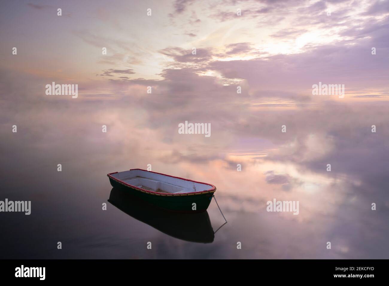 Barca ormeggiata su un mare calmo contro il cielo nuvoloso durante il tramonto Foto Stock