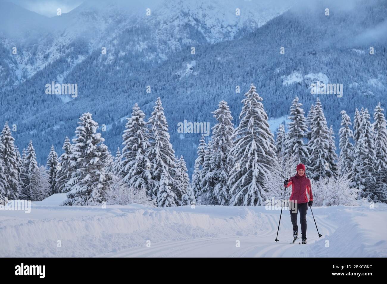 Donna anziana che sciava con polo di sci sulla neve sopra la montagna Foto Stock