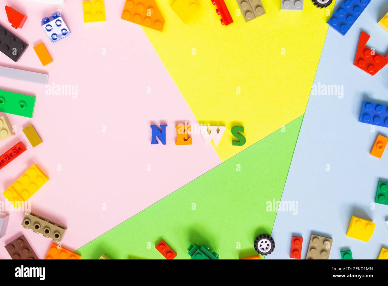 Parole fatte di lettere di legno multicolore 'notizie' su uno sfondo multicolore, kit di costruzione per bambini intorno. Vista dall'alto. Foto Stock