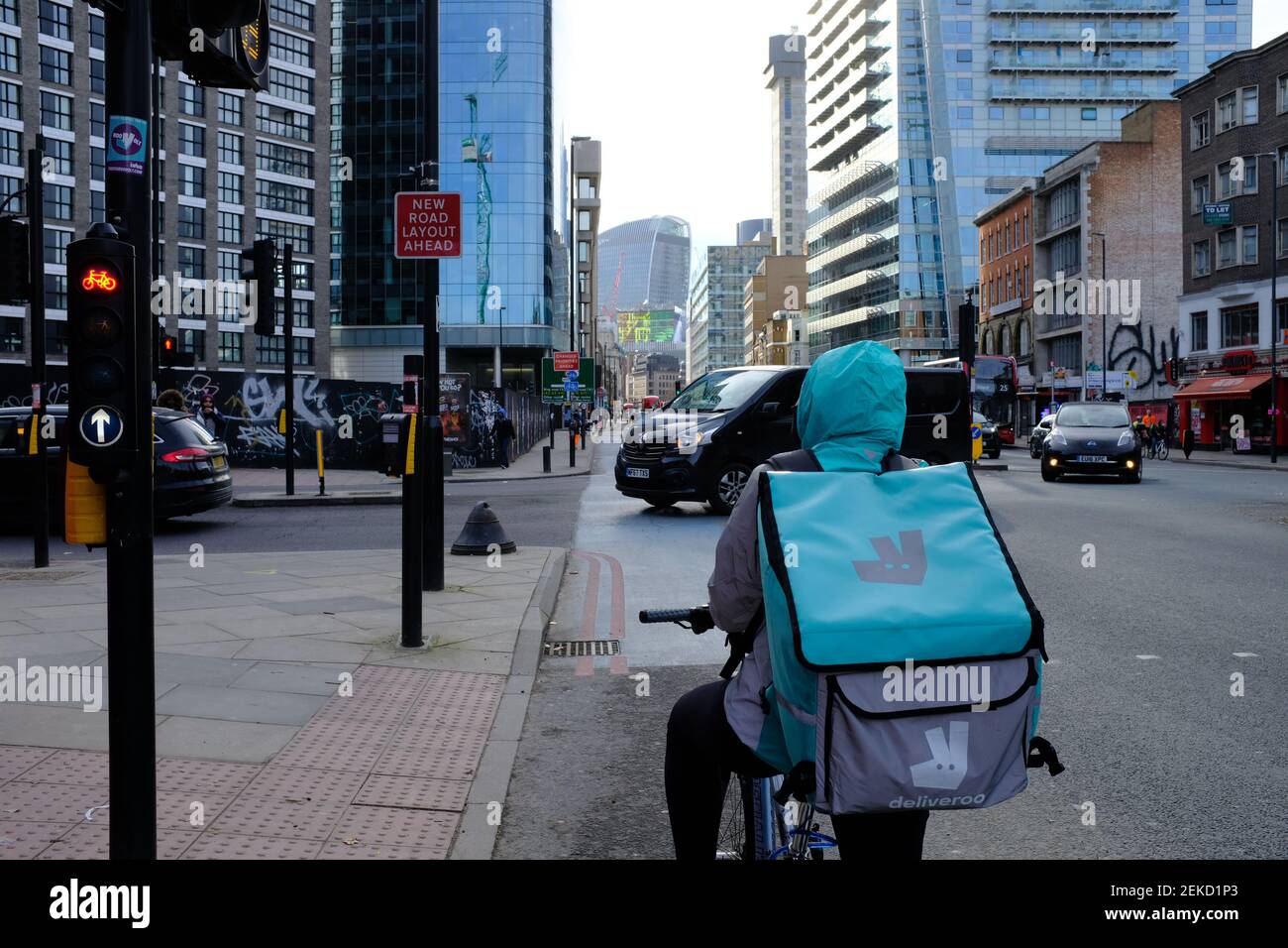 LONDRA - 23 FEBBRAIO 2021: Un corriere Deliveroo food in attesa al semaforo di Aldgate. Foto Stock