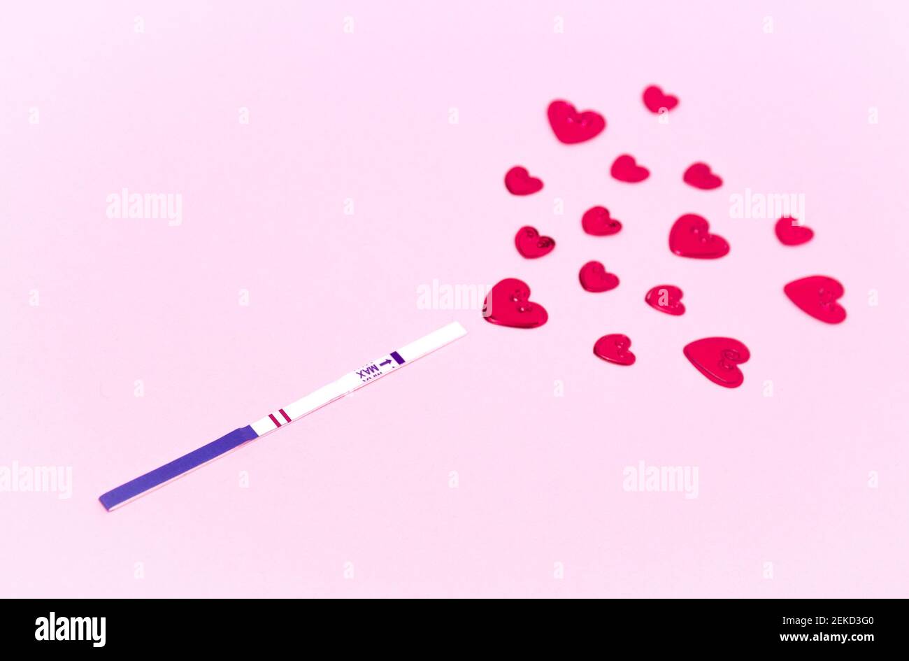 Una striscia di prova di gravidanza positiva e cuori rossi. Il concetto di concepimento, l'attesa di un bambino, una famiglia. Foto Stock