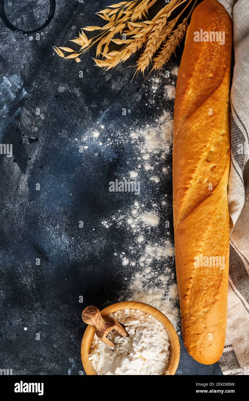 Pane fresco francese baguette, farina di grano e spighe su vecchio tavolo grigio di fondo in cemento. Vista dall'alto in piano con spazio per la copia Foto Stock