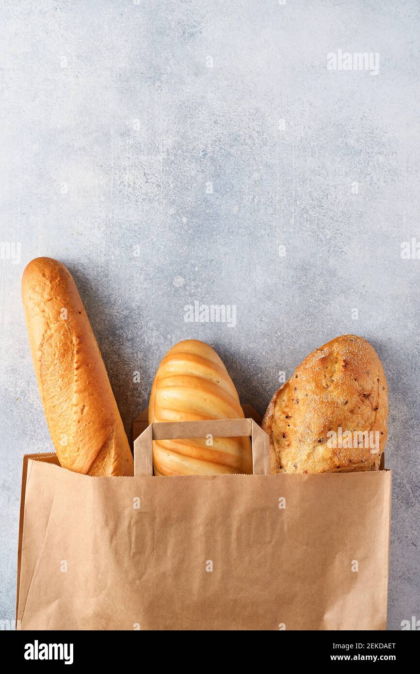 Pane mescolato in un sacchetto di carta su un tavolo di pietra di cemento grigio chiaro. Vista dall'alto con spazio per la copia Foto Stock