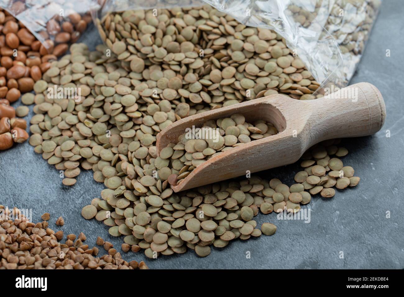 Un cucchiaio di legno con lenticchie brune secche crude Foto Stock