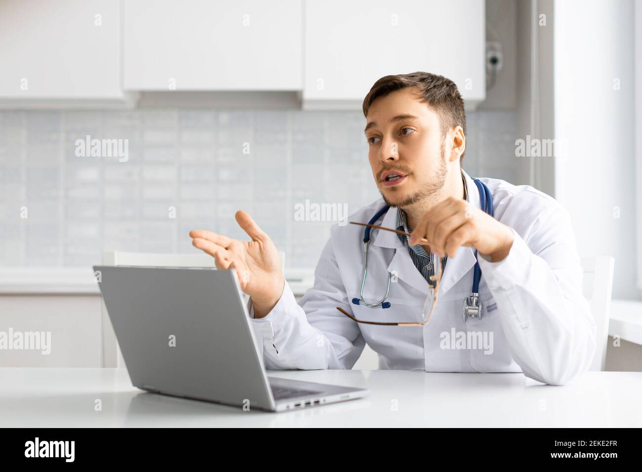 Medico durante una videochiamata online davanti a un monitor portatile. Comunica con il paziente e fornisce consigli sul trattamento. Concetto di assistenza sanitaria. Foto Stock