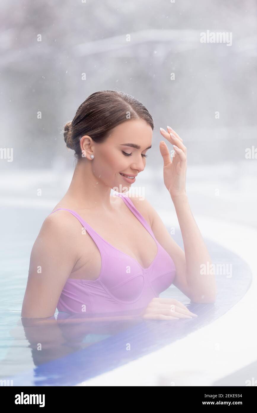 vapore vicino sorridente giovane donna che bagna in una sorgente calda esterna piscina Foto Stock